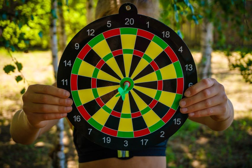 person holding dart board with dart in it