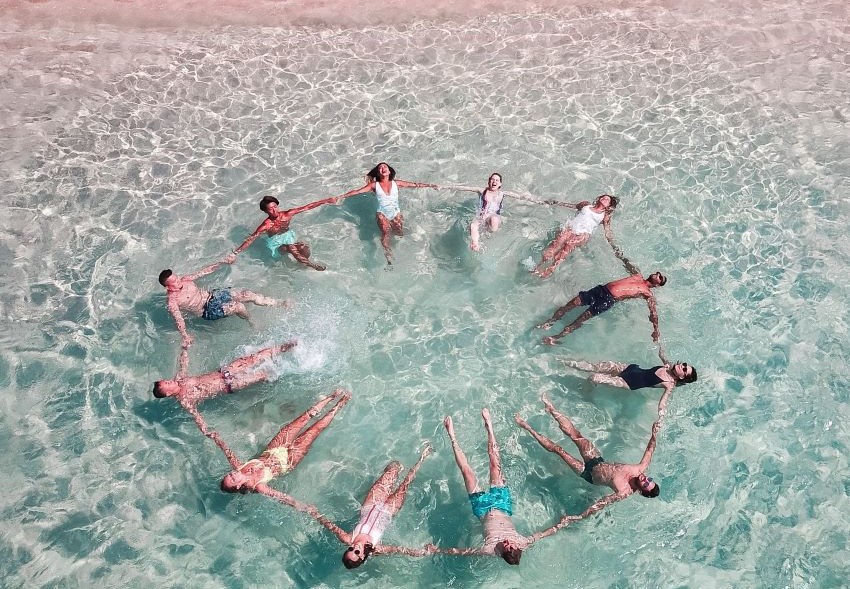 people in the sea holding hands forming circle