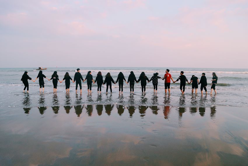 people standing in the ocean holding hands 