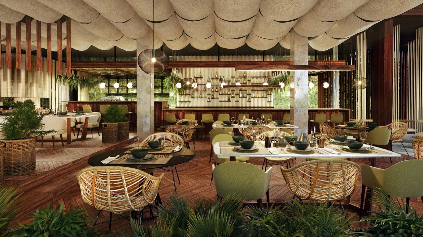 A cozy, modern restaurant with green and wicker chairs, wooden tables, and hanging globe lights. The ceiling has cloud-like panels, creating a welcoming ambiance.