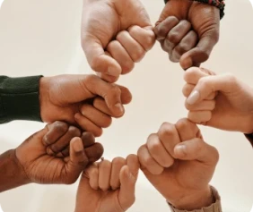 Eight diverse hands forming a circle with pinky fingers interlocked. The image conveys unity and teamwork against a neutral background.