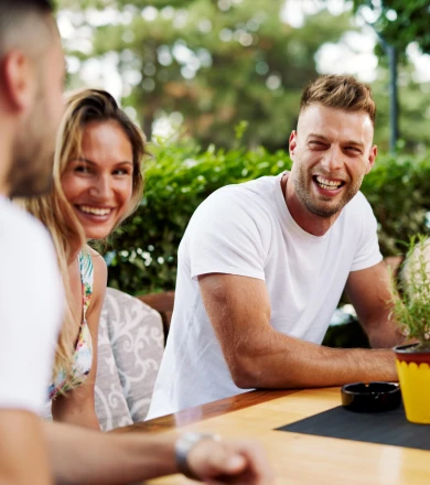 A group of four people sit at an outdoor table, laughing and enjoying each other's company.
