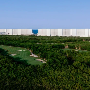 exterior of ava resort cancun with golf course and the ocean in the background