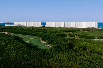 exterior of ava resort cancun with golf course and the ocean in the background
