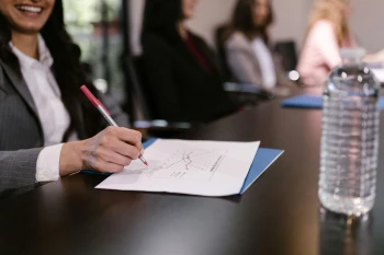 employee smiling and taking notes in a meeting