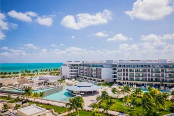 aerial view of Majestic Elegance Costa Mujeres with its pools and buildings and the beach