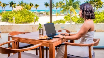 woman working on her laptop while enjoying a snack at the oceanfront restaurant at Majestic Elegance Costa Mujeres