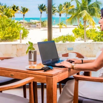 woman working on her laptop while enjoying a snack at the oceanfront restaurant at Majestic Elegance Costa Mujeres