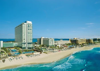 Aerial view of the modern high-rise Secrets The Vine Cancun resort on the white-sand beach.