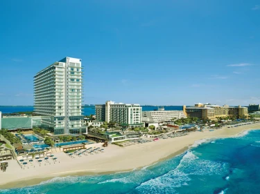 Aerial view of the modern high-rise Secrets The Vine Cancun resort on the white-sand beach.