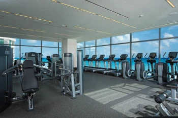 Ocean-view fitness center with treadmills and weight machines at Secrets The Vine Cancun.