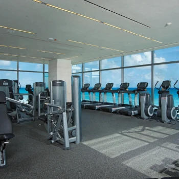 Ocean-view fitness center with treadmills and weight machines at Secrets The Vine Cancun.