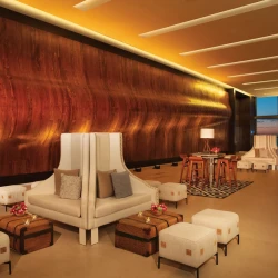 Elegant foyer with a textured wooden wall, stylish white seating for a cocktail or group event setup.