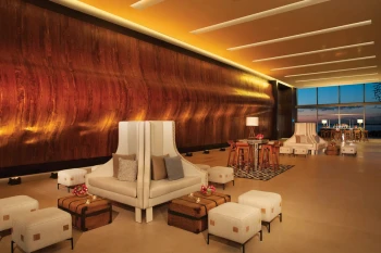 Elegant foyer with a textured wooden wall, stylish white seating for a cocktail or group event setup.