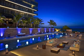 Elegant poolside event at night with blue uplighting, palm trees, and illuminated floating orbs.