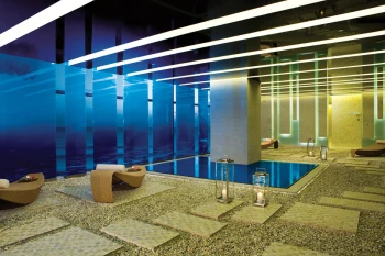 Modern and serene hydrotherapy area in the Secrets Spa with blue and yellow mood lighting.