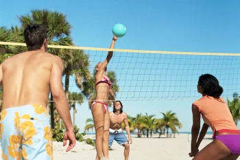 Team-building in action! Colleagues enjoy a fun game of beach volleyball on the sand at Secrets The Vine Cancun during their corporate retreat.
