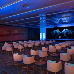 Large resort ballroom set up theater-style for a meeting, illuminated with cool blue event lighting.