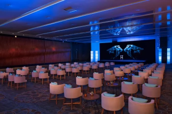 Large resort ballroom set up theater-style for a meeting, illuminated with cool blue event lighting.